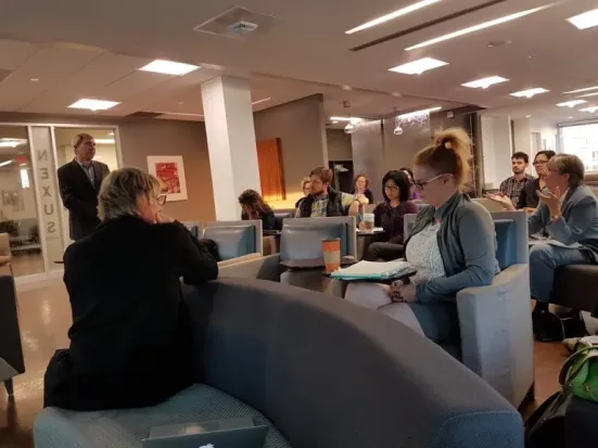 A group of people seated and talking in the OISE Nexus Lounge.