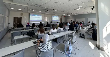 A group of people watching a Symposium 2024 presentation.