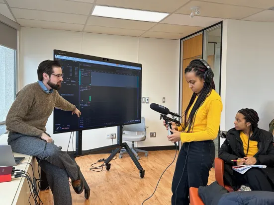 A person standing, being recorded by another while they speak