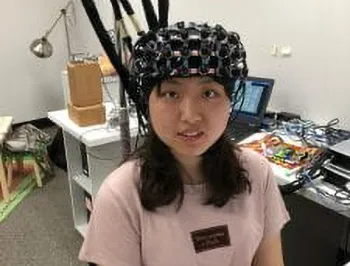 A person seated and wearing a helmet to understand their brain.