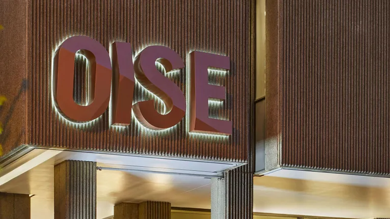 The OISE building sign illuminating at night.