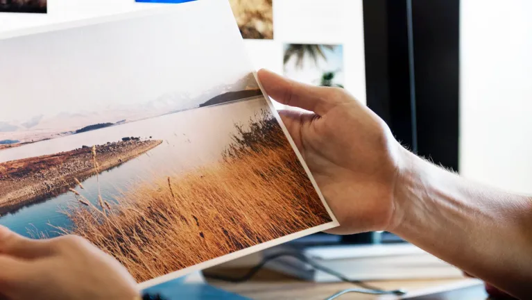 Two hands holding a printed photo of a landscape.