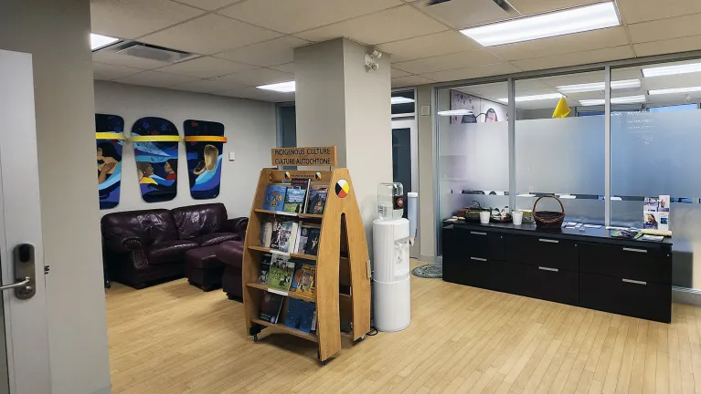 Entrance lobby of the IEN. A book case is in the middle of the room, with offices on the right and couches on the left in the background.