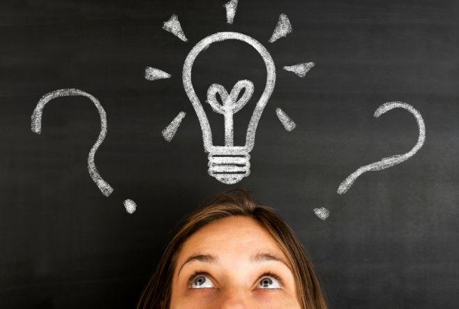 head on a blackboard background with a light bulb and question marks drawn.